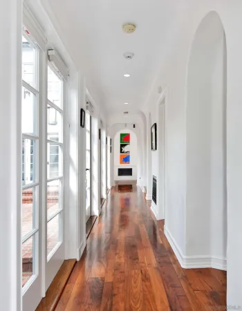 a view of a hallway with wooden floor and windows