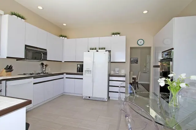 a kitchen with granite countertop a refrigerator and a stove top oven