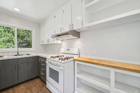a kitchen with a refrigerator a stove top oven and wooden floor