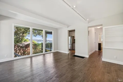 a view of an empty room with wooden floor and windows