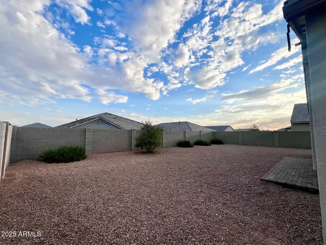 a view of a dry yard with wooden fence