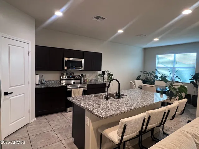 a kitchen with a stove a sink a microwave a dining table and chairs