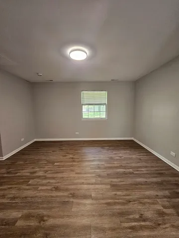 a view of an empty room with wooden floor and window