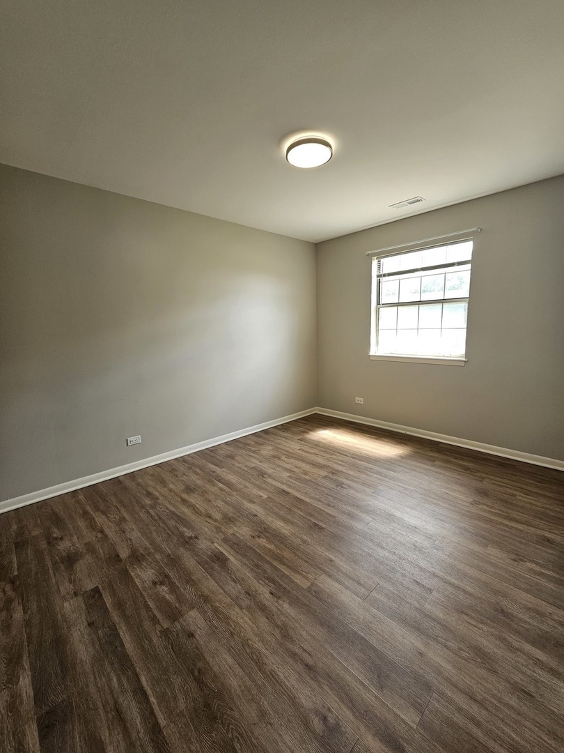 56 North Victoria Lane, Unit C Streamwood, IL 60107 - Photo 5 of 11 an empty room with wooden floor and windows