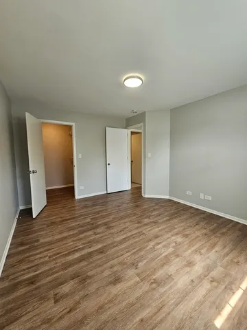a view of an empty room with wooden floor and closet