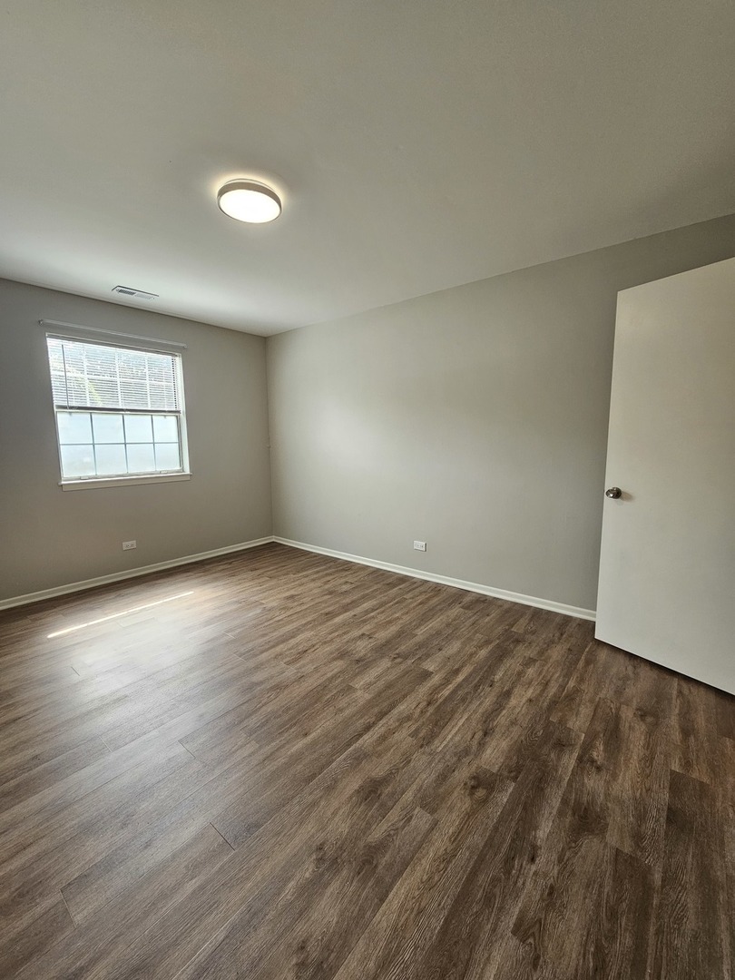 56 North Victoria Lane, Unit C Streamwood, IL 60107 - Photo 8 of 11 an empty room with wooden floor and windows