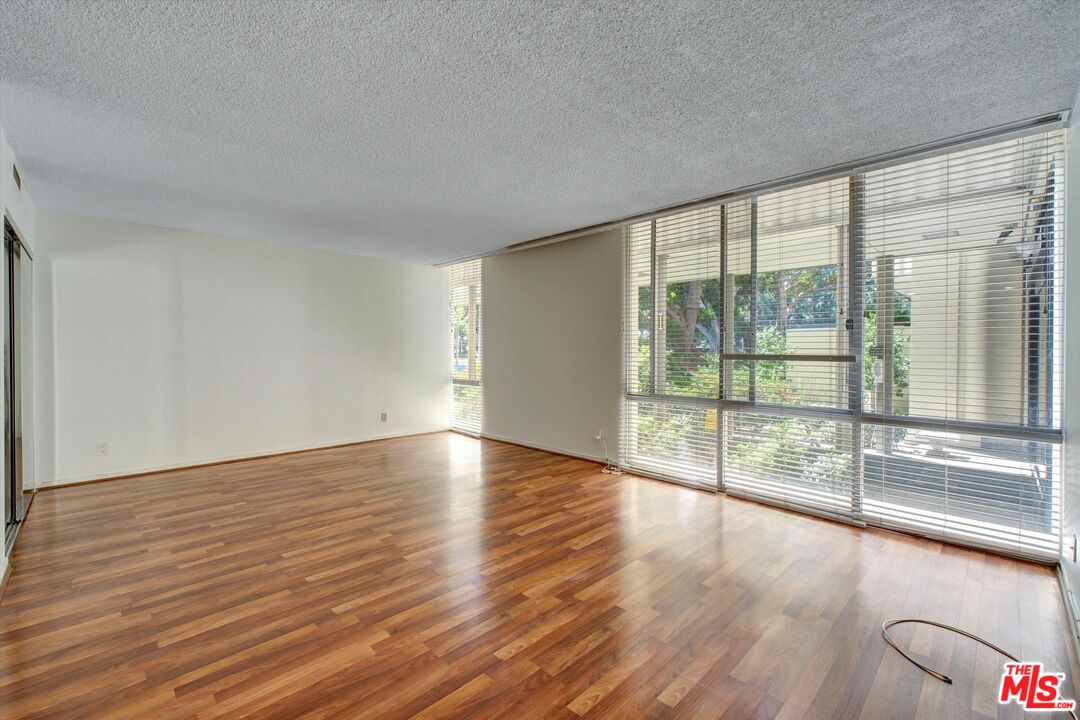 2160 Century Park East, Unit 103 Los Angeles, CA 90067 - Photo 2 of 37 a view of an empty room with wooden floor and a window