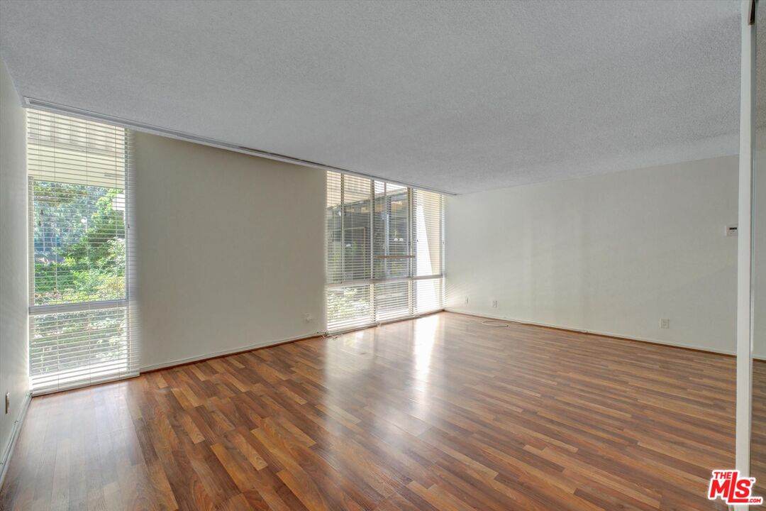 2160 Century Park East, Unit 103 Los Angeles, CA 90067 - Photo 3 of 37 a view of an empty room with wooden floor and a window