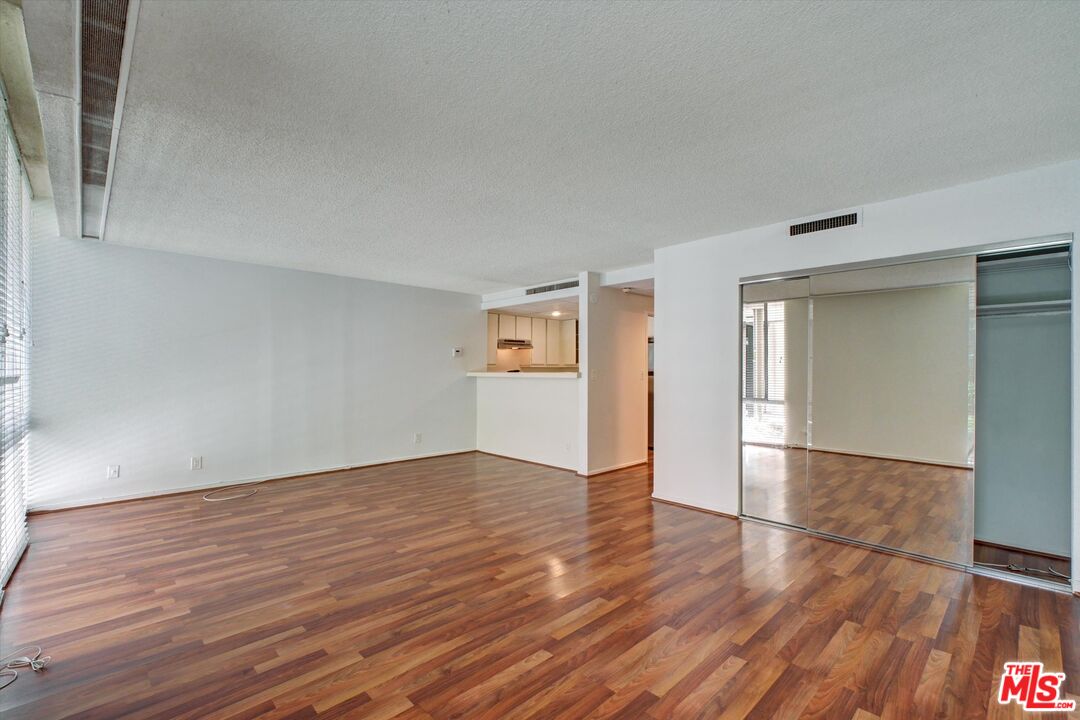 2160 Century Park East, Unit 103 Los Angeles, CA 90067 - Photo 4 of 37 a view of an empty room with wooden floor and a window