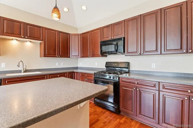 a kitchen with granite countertop a stove top oven microwave and cabinets