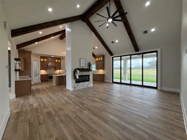 a view of an empty room with wooden floor and windows