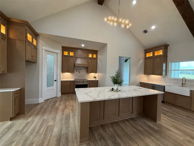 a large kitchen with stainless steel appliances granite countertop a lot of counter space and wooden floors