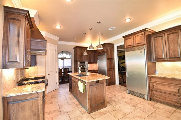 a kitchen with stainless steel appliances granite countertop a refrigerator a stove and a sink