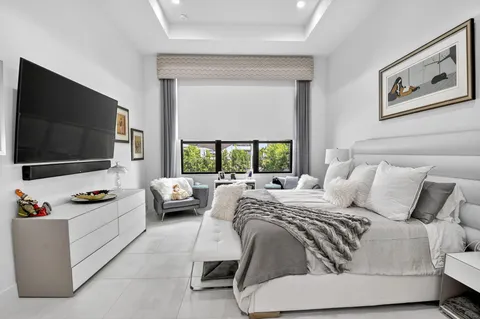 a bedroom with bed and a flat tv screen on the dresser
