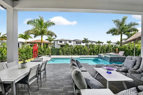 a view of a patio with couches potted plants and a large tree