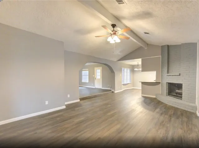 a view of an empty room with a fireplace and wooden floor
