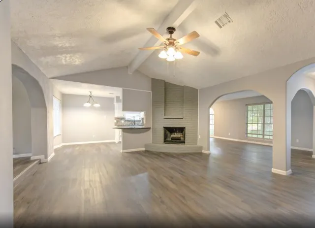 an empty room with wooden floor fireplace and staircase