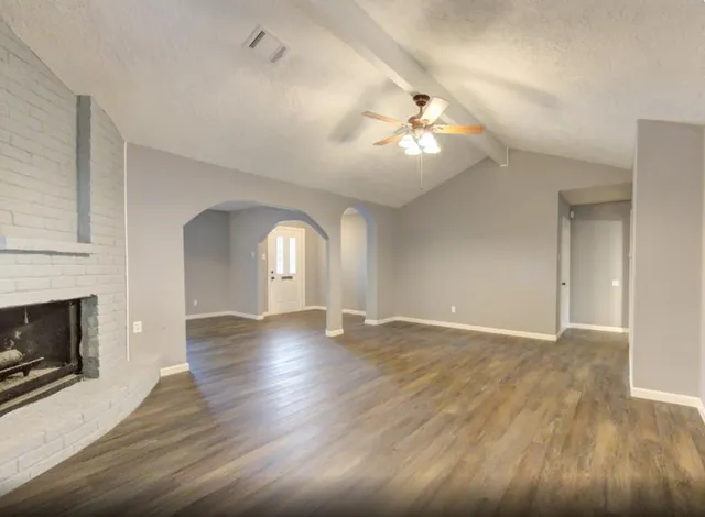 a view of empty room with wooden floor and fireplace