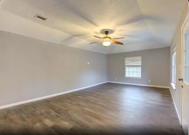 an empty room with window and wooden floor
