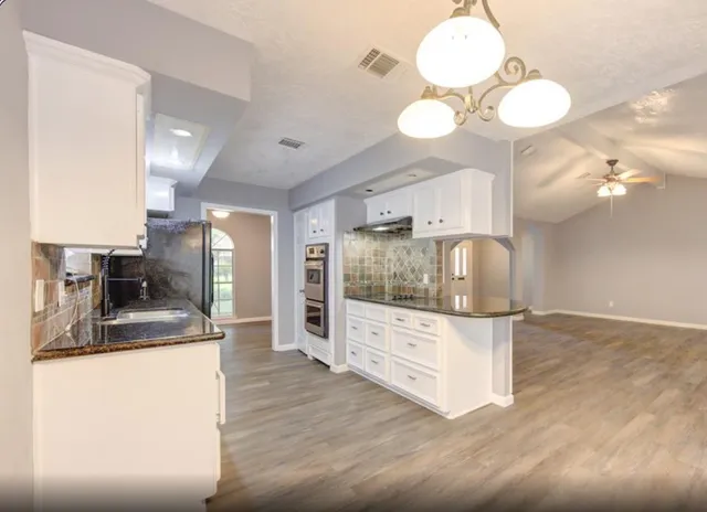 a kitchen with stainless steel appliances granite countertop a sink a stove and a wooden floors