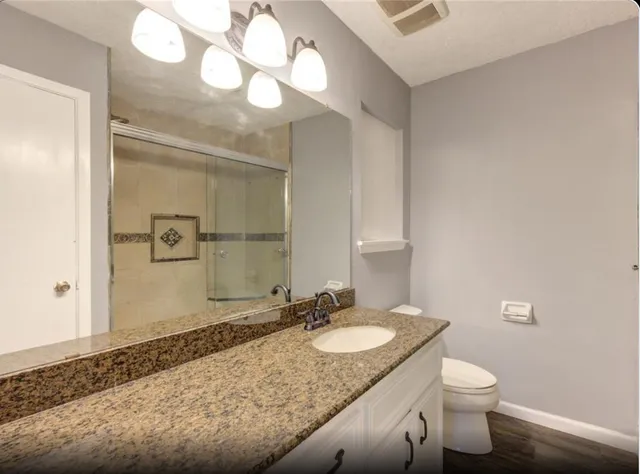 a bathroom with a granite countertop sink a toilet and a mirror