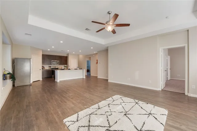 a view of an empty room with chandelier fan and windows