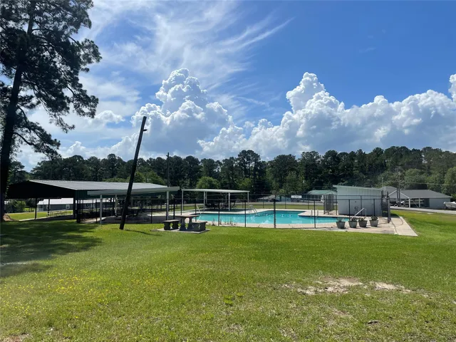 a view of a swimming pool with lawn chairs and a big yard