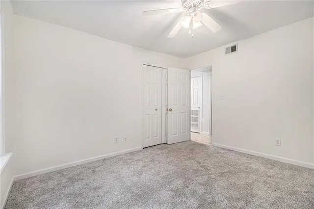 an empty room with a chandelier fan and windows