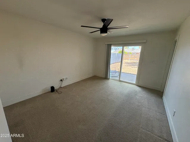 an empty room with a ceiling fan and window