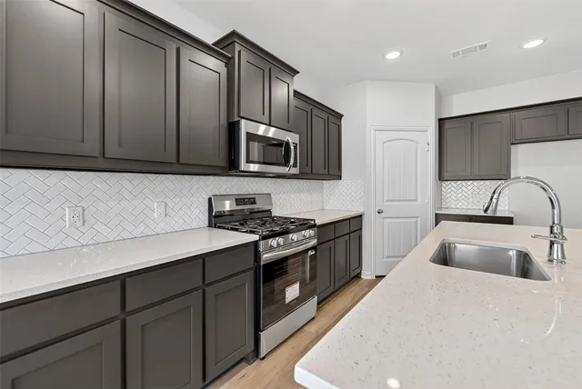 a kitchen with stainless steel appliances granite countertop a sink stove and microwave