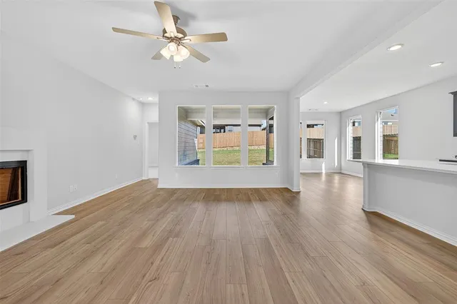 a view of an empty room with window and wooden floor