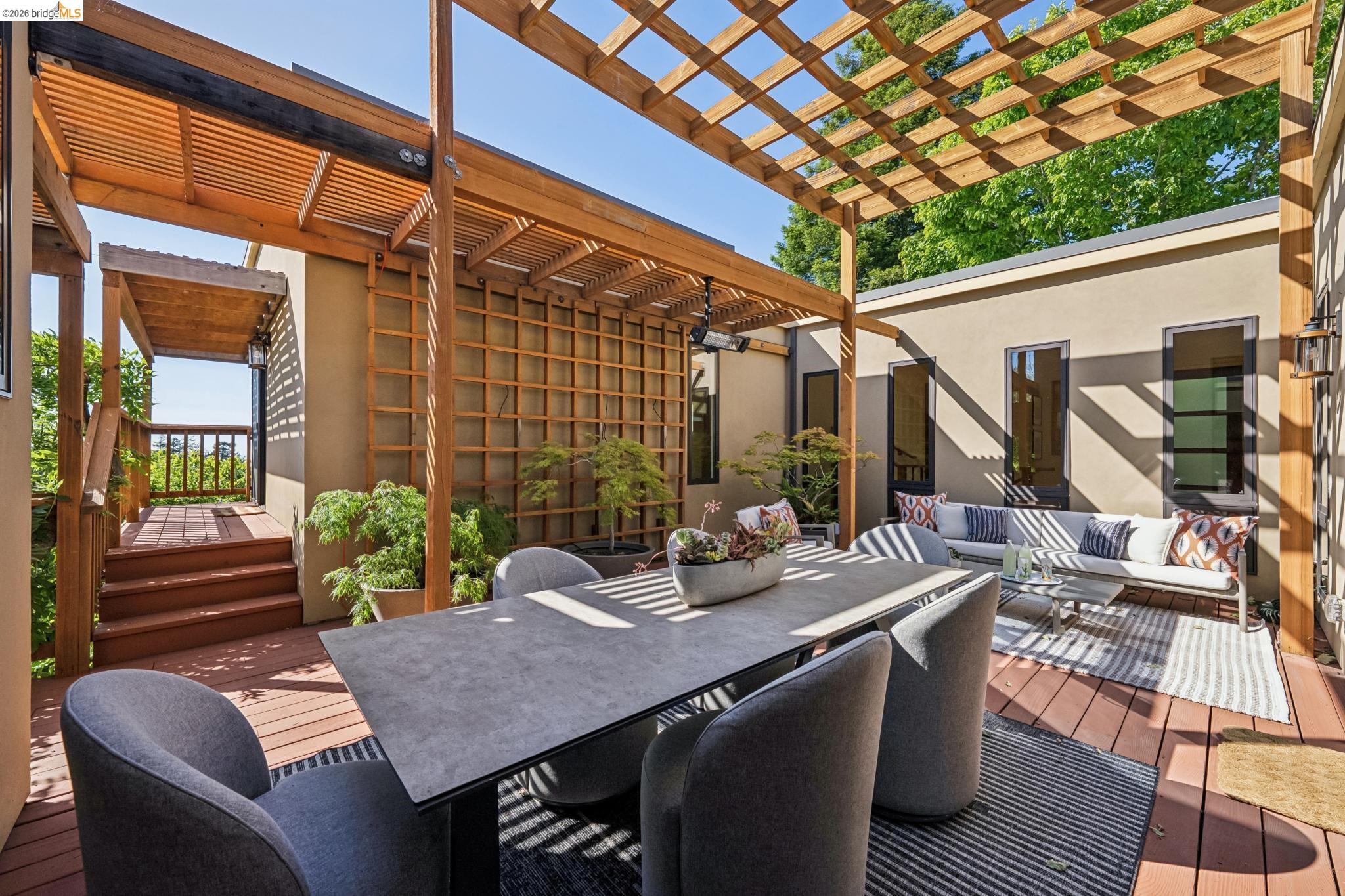 576 Vistamont Avenue Berkeley, CA 94708 - Photo 15 of 33 Expansive outdoor deck featuring a wooden pergola, stucco exterior, multiple window openings, and an exterior staircase