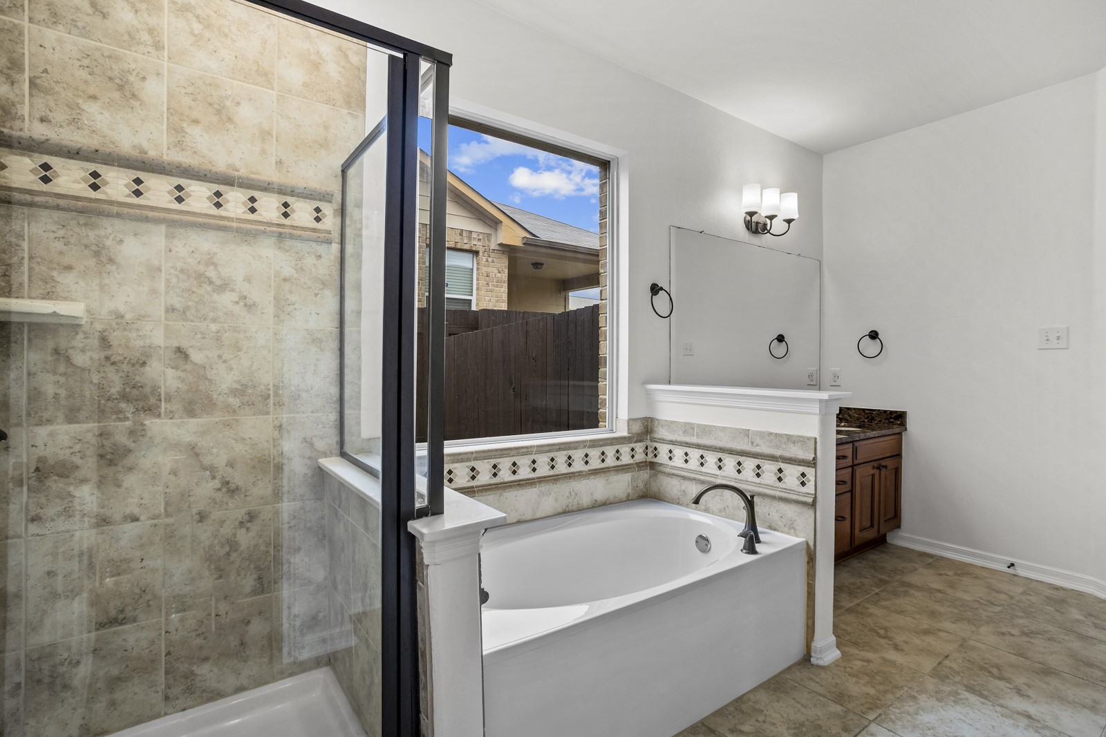 245 Razzmatazz Trail Buda, TX 78610 - Photo 20 of 37 Bathroom featuring a walk-in shower with glass enclosure, a built-in bathtub, a window, a vanity with a cabinet, and tile flooring