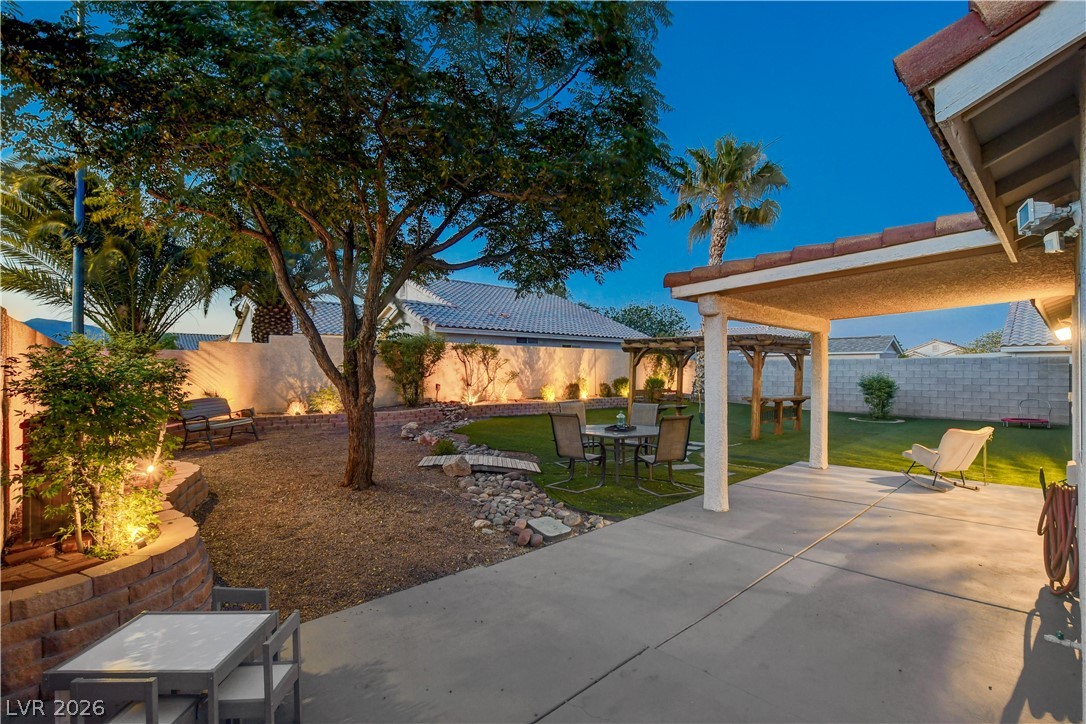 910 Cobblestone Cove Road North Las Vegas, NV 89081 - Photo 22 of 30 Illuminated by night, this private yard boasts a covered patio, pergolas, and mature landscaping for serene outdoor living.