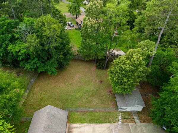 an aerial view of a residential houses with outdoor space and trees all around