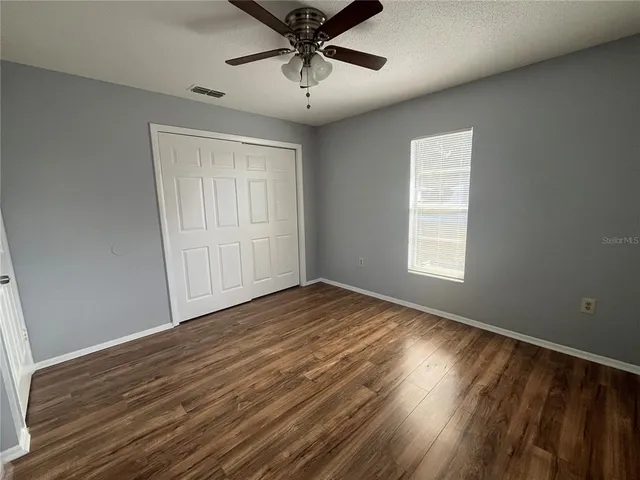 a view of empty room with wooden floor and fan