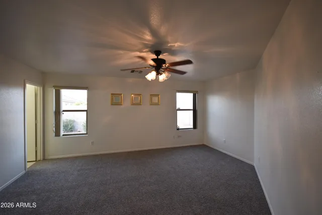 an empty room with windows and ceiling fan