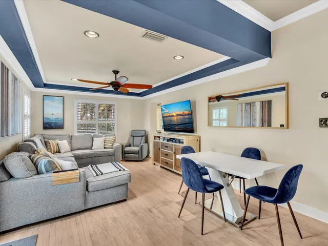 a kitchen with stainless steel appliances kitchen island granite countertop a refrigerator a sink a stove and white cabinets with wooden floor