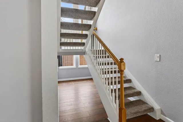 a view of staircase with wooden floor and white walls