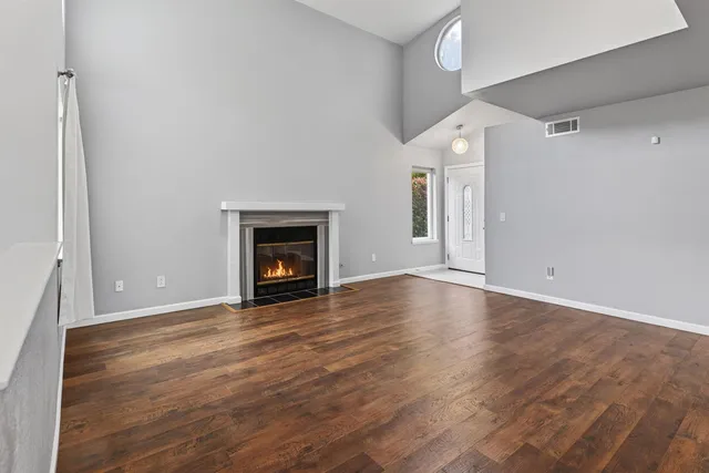 a view of empty room with wooden floor and fireplace