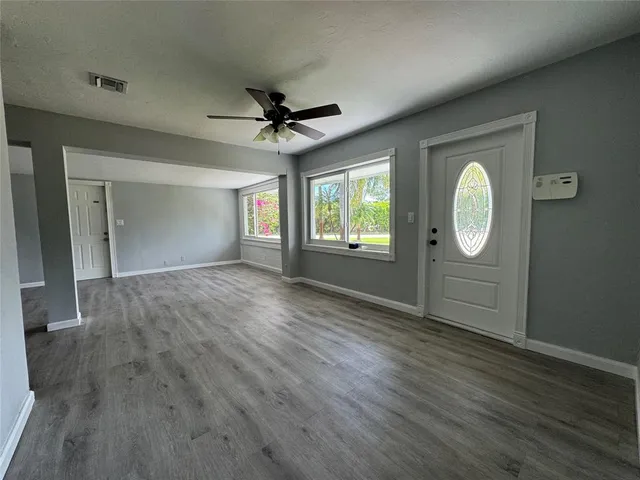 a view of an empty room with a window and wooden floor