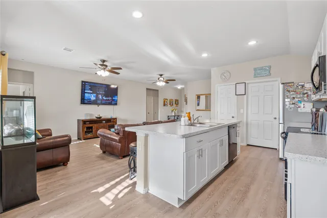 a large white kitchen with lots of counter space a sink and stainless steel appliances