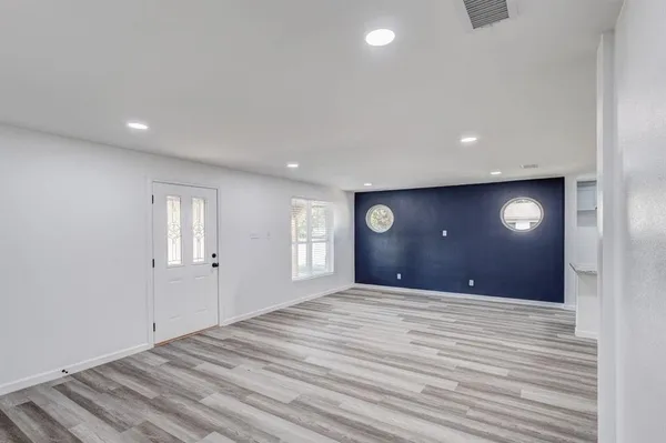 a view of an empty room with window and wooden floor