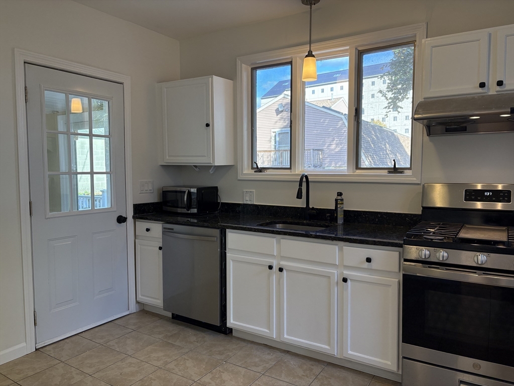 57 Coburn Avenue, Unit 2 Worcester, MA 01604 - Photo 11 of 42 a kitchen with granite countertop a stove a sink and a window