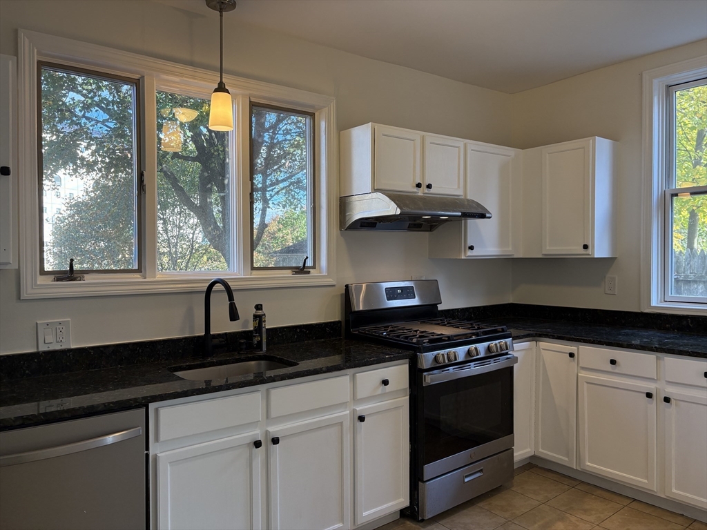 57 Coburn Avenue, Unit 2 Worcester, MA 01604 - Photo 12 of 42 a kitchen with granite countertop white cabinets appliances a large window and a counter space