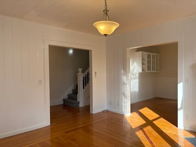 an empty room with wooden floor and chandelier