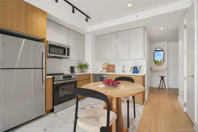 a open kitchen with stainless steel appliances granite countertop a stove a refrigerator a sink dishwasher a dining table and chairs with wooden floor
