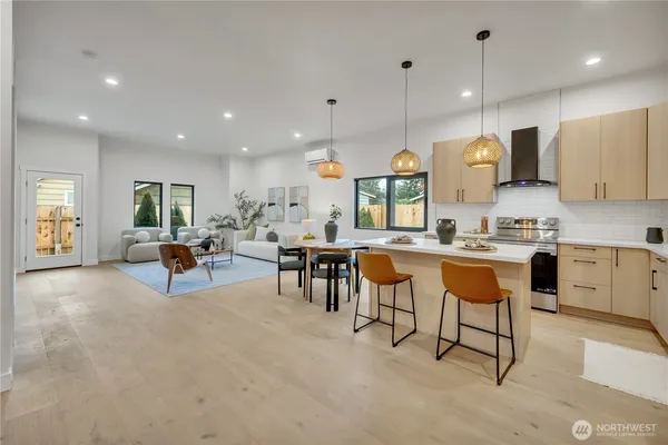 a kitchen with stainless steel appliances kitchen island granite countertop a table chairs sink and cabinets