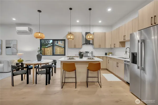 a kitchen with stainless steel appliances granite countertop a sink a stove a refrigerator a dining table and chairs with wooden floor