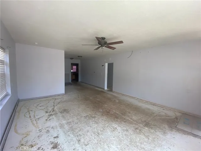 an empty room with a ceiling fan and window